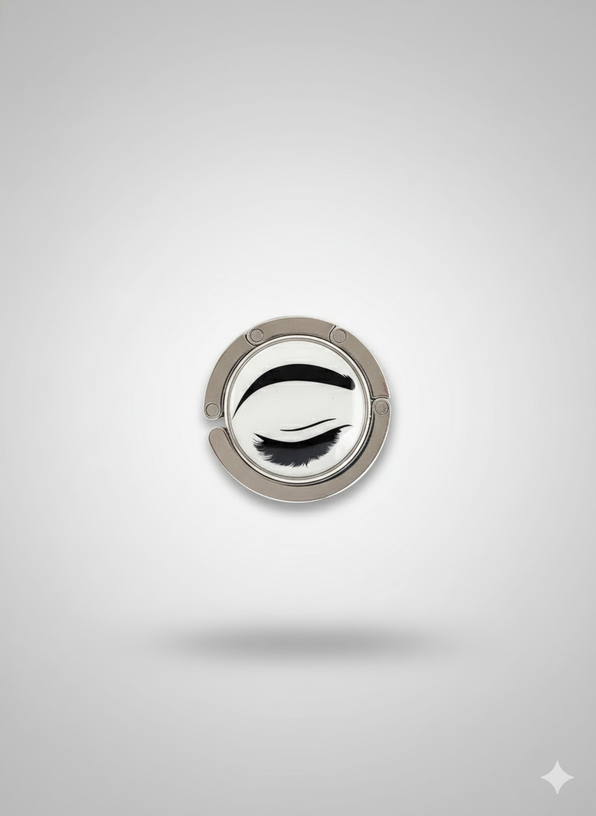 Silver ring holder with black eye design on a light gray background