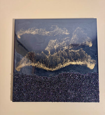 Abstract art piece with gold and black patterns on a beige wall