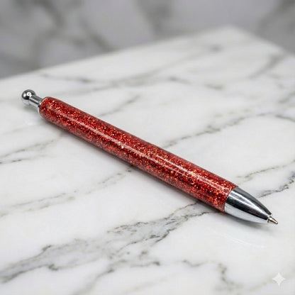 Chunky Orange glitter pen with silver accents on a marble surface