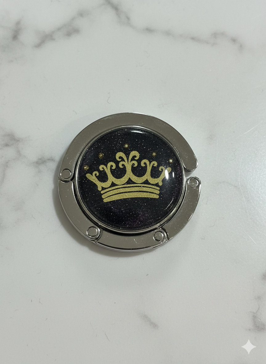 Round metallic object with a yellow crown design on a marble surface