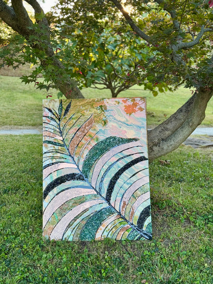Colorful abstract leaf painting and resin art on grass with trees in the background