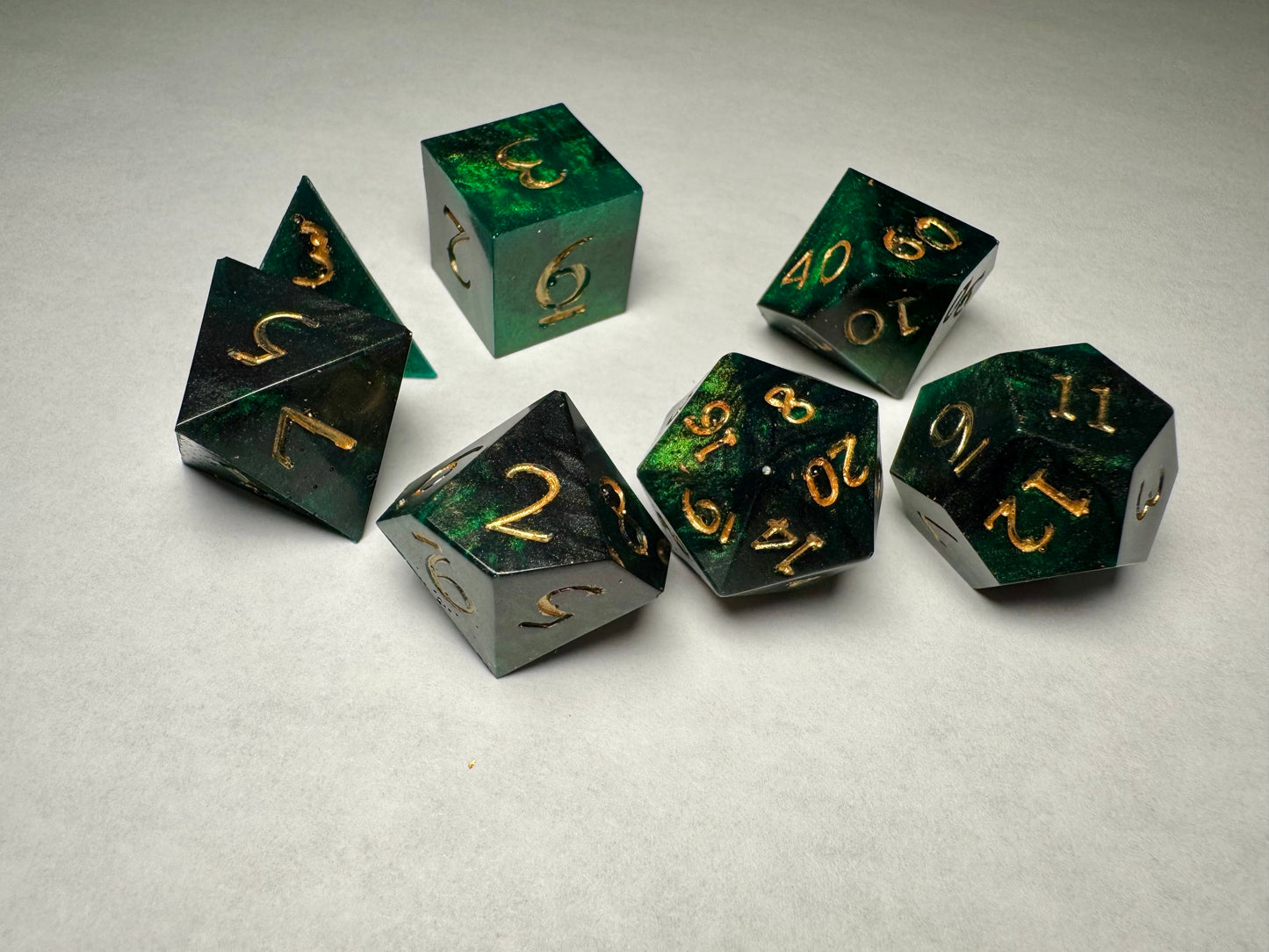 Set of green and black dice with gold numbers on a light gray background