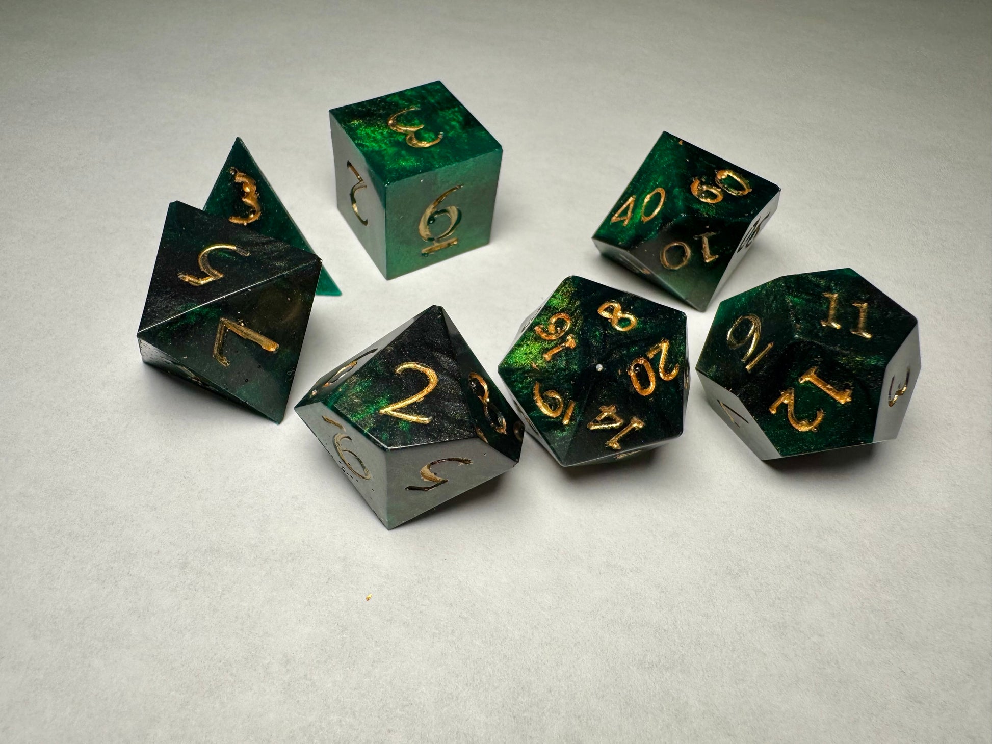Set of green and black dice with gold numbers on a light gray background