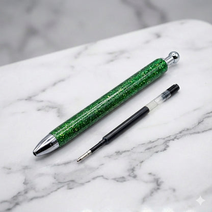 Green glitter pen with silver accents on a marble surface