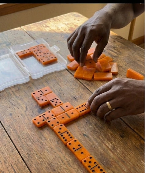 Person playing with orange dominoes on a wooden table