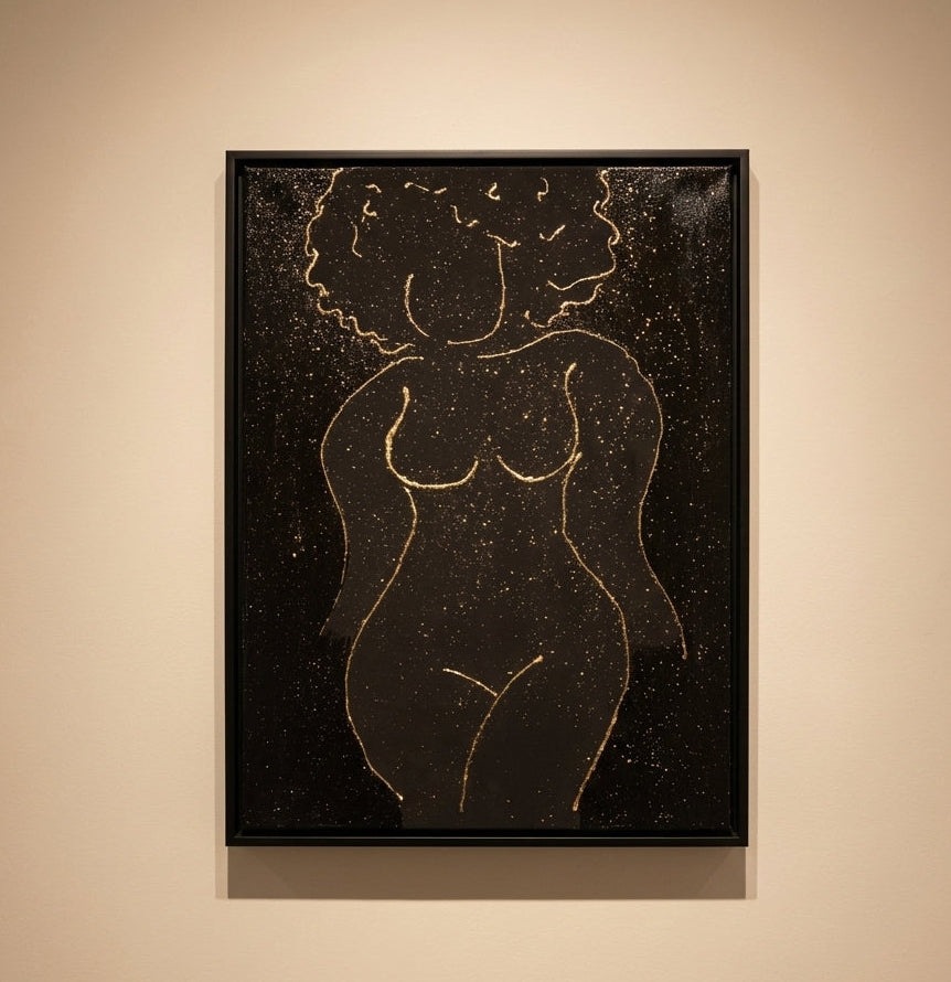 Framed artwork of a nude figure with gold lines on a black background, displayed on a beige wall.