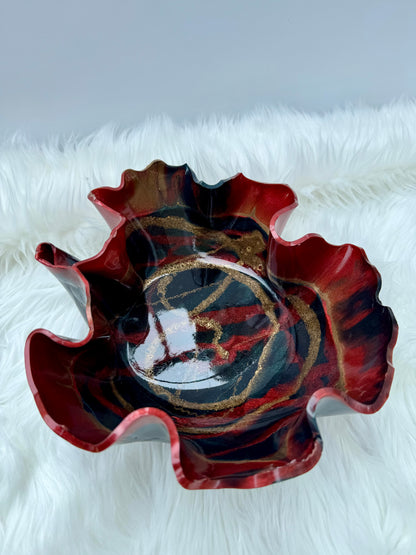 Decorative glass bowl with red and black design on a white fur surface