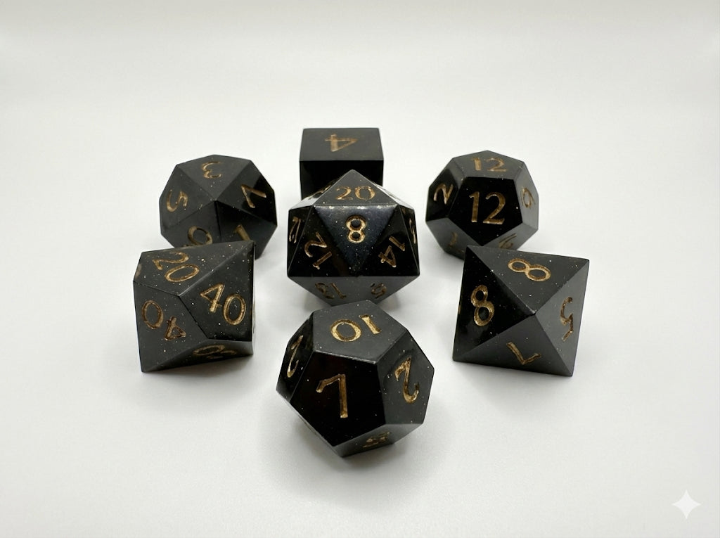 Set of black polyhedral dice with gold numbers on a white background