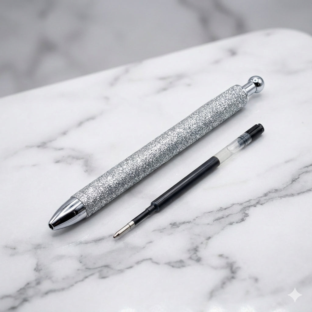 Silver glitter pen with a black pen tip on a marble surface