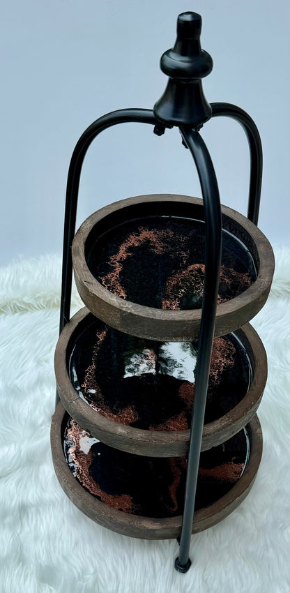 Three-tiered metal stand with black handle on a white surface