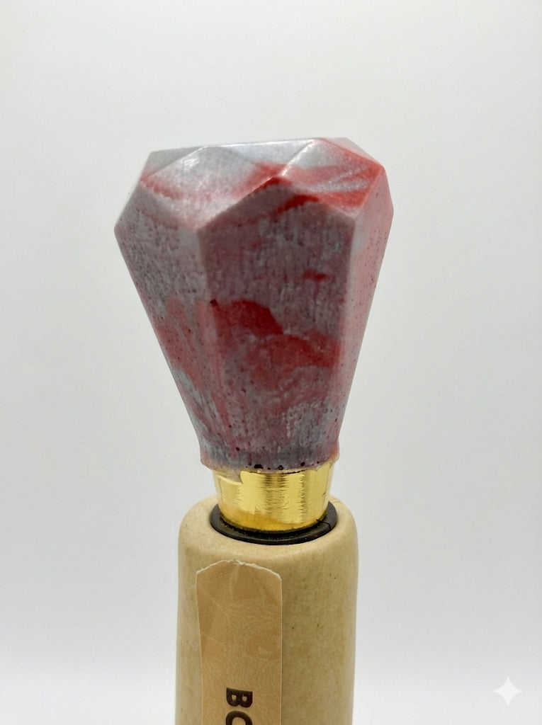 Decorative bottle stopper with red and gray stone top on a white background