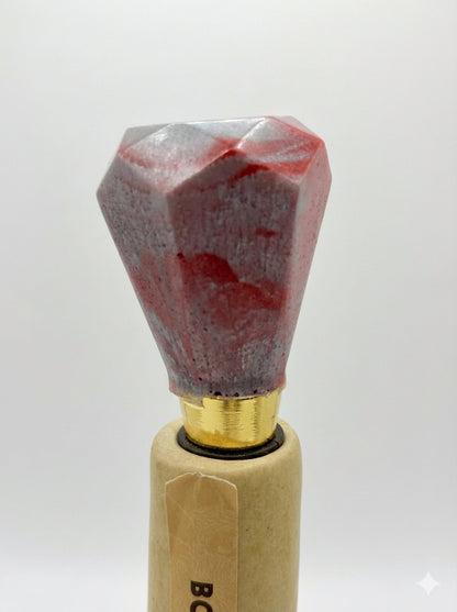 Decorative bottle stopper with red and gray stone top on a white background