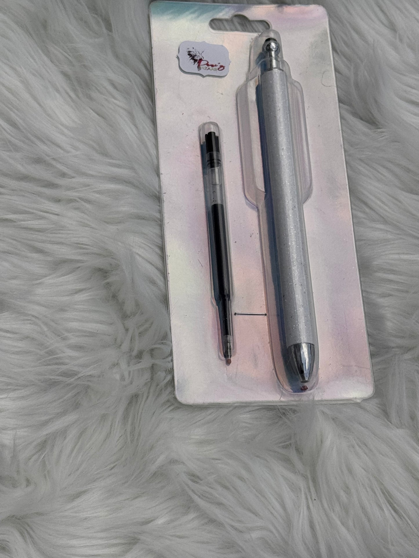 A glittery white stylus pen and a black ink pen displayed on a white iridescent backing card, set against a white faux fur background.