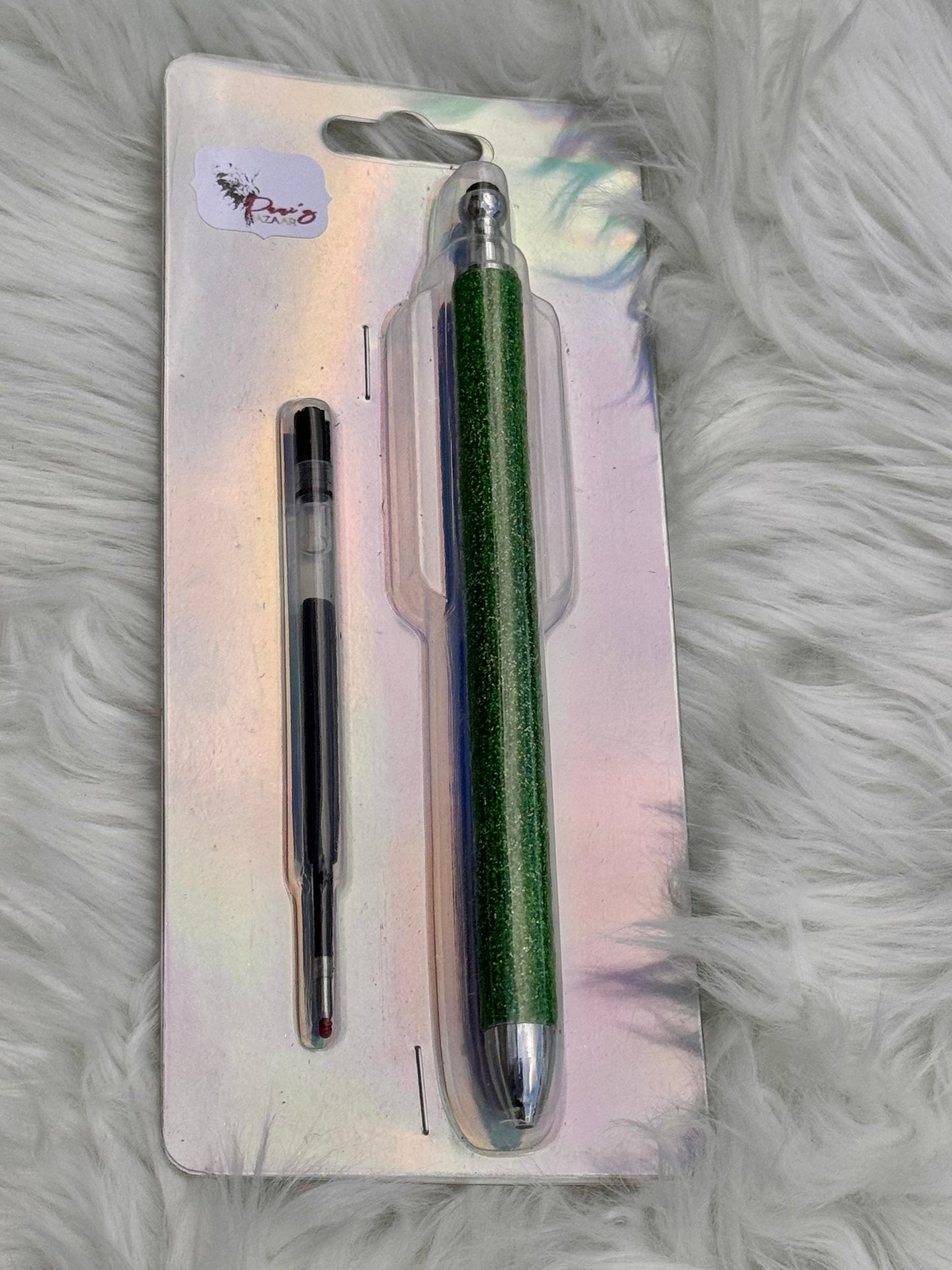 A green glittery dual-ended stylus pen with a black and clear refill, packaged on a holographic backing card over a white faux fur background.