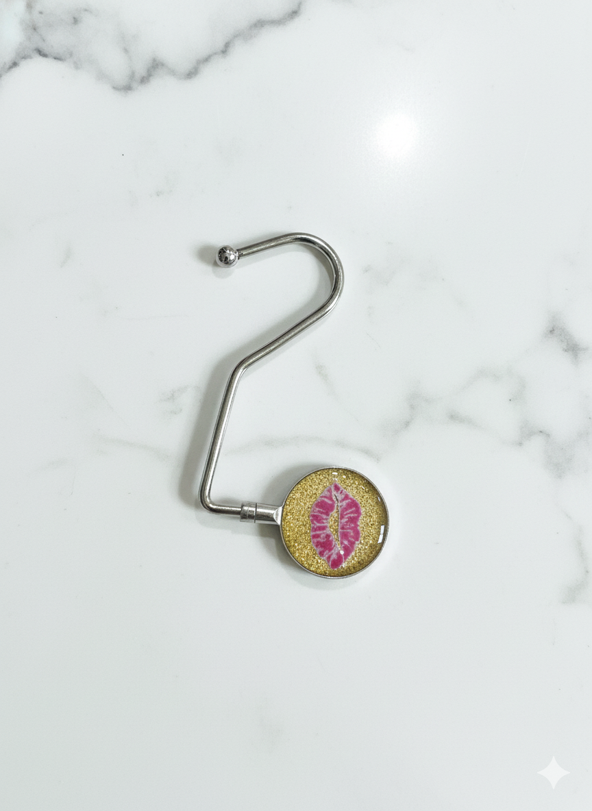 Metallic bag hook with a decorative circular end on a marble surface