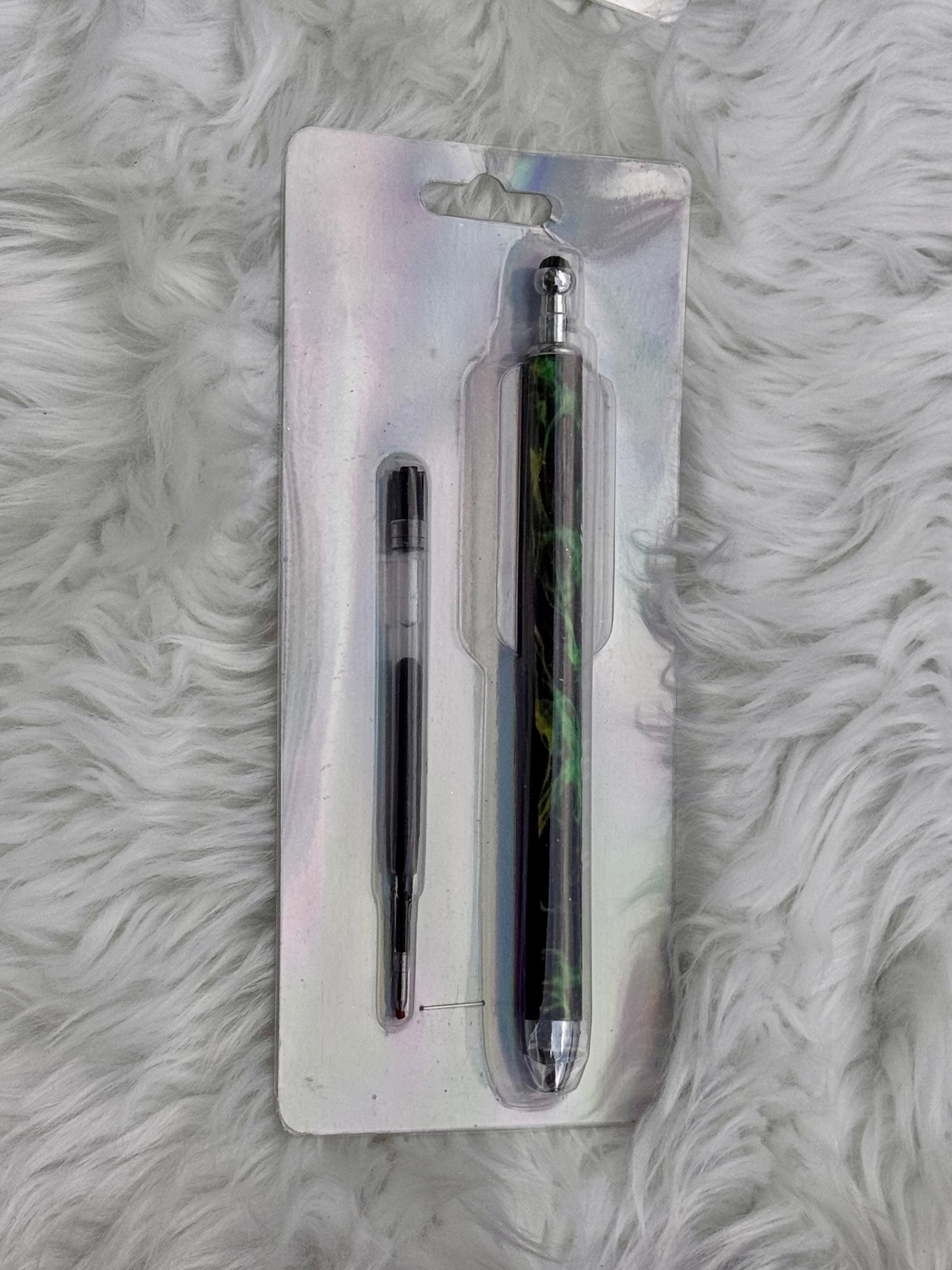 A two-piece pen set in blister packaging, featuring a slim black pen and a larger pen with a green and black marbled pattern, displayed on a white faux fur background.