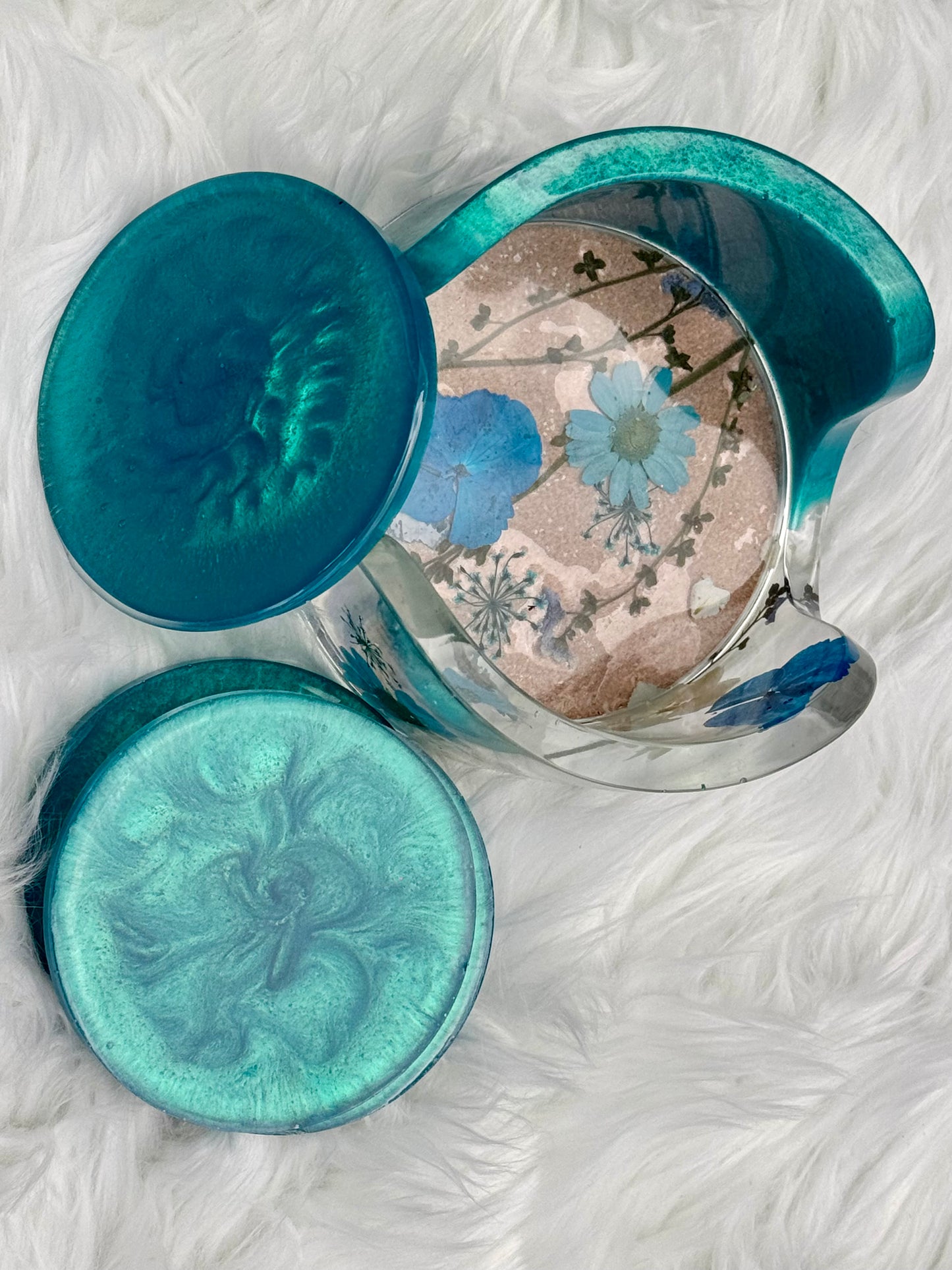 Set of four coasters, blue with the container housing pressed flowers inside of the resin